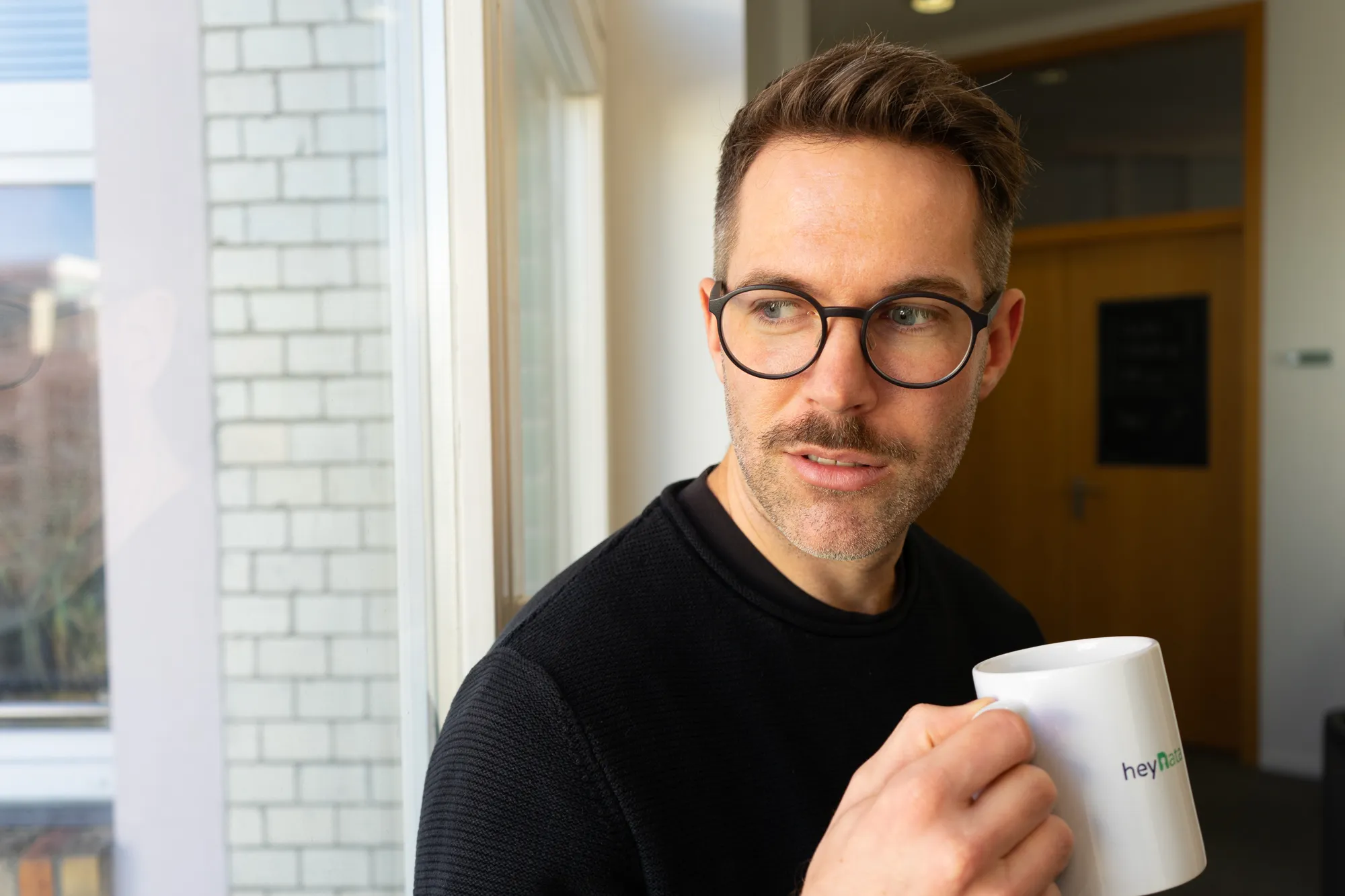 Michael drinking coffee out of a heyData mug